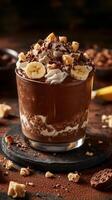 Delicious chocolate dessert featuring layers of cream, banana slices, and chocolate crumbles in a stylish glass photo