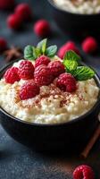 Creamy rice pudding topped with fresh raspberries and mint leaves on a textured surface photo