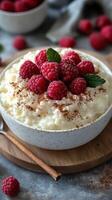 Creamy rice pudding topped with fresh raspberries and mint leaves served on a wooden board photo