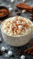 Warm bowl of creamy dessert topped with marshmallows and spices in a cozy setting photo