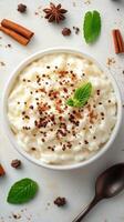 Creamy rice pudding topped with chocolate and mint served in a white bowl with spices around photo