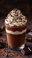 Creamy chocolate dessert topped with whipped cream and chocolate shavings in a clear glass photo