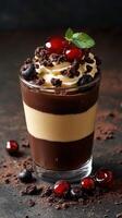 Delicious chocolate and vanilla dessert layered with cherry and mint garnishes served in a glass photo