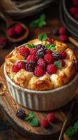 Delightful berry bread pudding topped with fresh raspberries and blackberries on a rustic wooden table photo