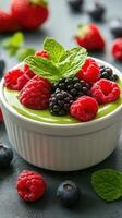 Delicious green dessert topped with fresh raspberries, blackberries, and mint served on a dark surface photo