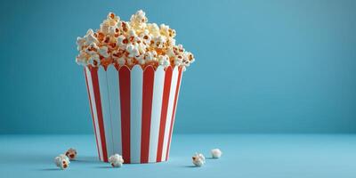 Popcorn in a classic striped container on a blue background ready for movie night or a snack time treat photo