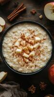 Warm bowl of creamy oatmeal topped with diced apples and cinnamon on a rustic wooden table photo