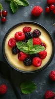 Fresh mixed berries with creamy dessert topped with mint leaves in a black bowl photo