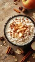 Warm oatmeal bowl topped with cinnamon, apple slices, and nuts displayed on a rustic surface photo
