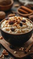 Creamy rice pudding topped with nuts and dried fruits on a rustic wooden surface in warm lighting photo