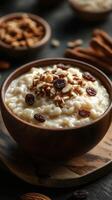 Creamy rice pudding topped with nuts and raisins served in a wooden bowl on a rustic table photo