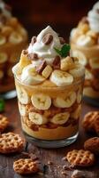 Delicious banana pudding dessert layered with whipped cream and cookies served in clear glass cups photo