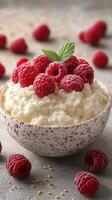 Creamy dessert topped with fresh raspberries and mint on a textured gray surface in a cozy kitchen setting photo