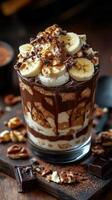 Delicious layered dessert with chocolate, bananas, and whipped cream garnished with nuts and cocoa powder photo