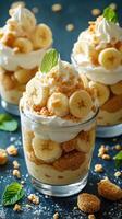 Delightful banana puddings topped with whipped cream and mint leaves served in glass cups at a dessert table photo