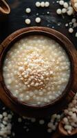 Creamy tapioca pudding served in a rustic bowl, garnished with sweet coconut flakes on a wooden surface photo