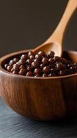 Delicious chocolate tapioca pearls in a wooden bowl with a spoon on a dark background photo
