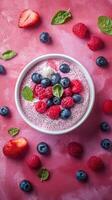 Colorful berry yogurt bowl with fresh fruit and mint on a pink background, showcasing healthy toppings for a vibrant breakfast photo