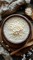 Delicious tapioca pearls in creamy dessert served in a rustic wooden bowl with a spoon photo