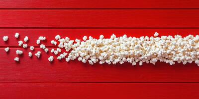 Popcorn scattered on a bright red wooden surface creating a playful contrast photo