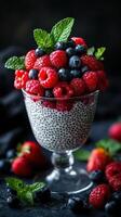 Delicious chia seed pudding topped with fresh berries and mint in a clear glass cup photo