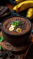Chocolate banana smoothie bowl topped with mint and chocolate chips between fresh bananas and dark chocolate photo