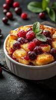 Delicious berry bread pudding with fresh raspberries and cherries garnished with mint photo