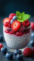 Delicious chia seed pudding topped with fresh berries and mint in a clear glass bowl photo