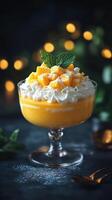 Mango dessert cup with whipped cream topped with fresh fruit and mint in a dimly lit setting photo
