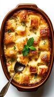 Bread pudding with a golden crust garnished with fresh mint leaves on a white background photo