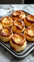 Freshly baked golden pastries arranged neatly on a baking tray on a marbled countertop photo