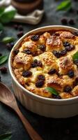 Delicious bread pudding with raisins and mint served in a white dish on a dark surface photo