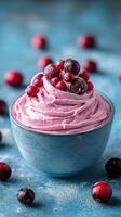 Delicious berry whipped dessert in a bowl surrounded by fresh berries on a blue background photo