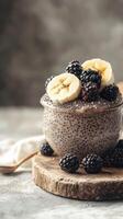 Creamy chia seed pudding topped with banana slices and blackberries in a rustic setting photo