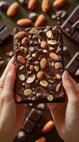 Delicious chocolate dessert topped with almonds and chocolate pieces held in hands photo