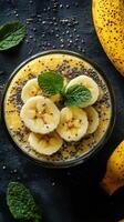 Smooth and creamy banana chia pudding topped with fresh banana slices and mint leaves on a dark background photo