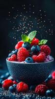 Vibrant berry bowl with fresh raspberries and blueberries garnished with mint leaves on a dark background photo