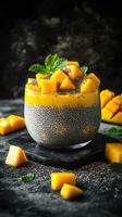 Delicious chia pudding topped with fresh mango and mint on a dark textured background photo