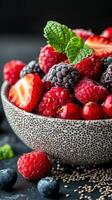 Fresh mixed berries in a decorative bowl with mint leaves on a dark background photo