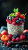 Delicious chia pudding with an assortment of fresh berries served in a glass with mint leaves against a dark background photo