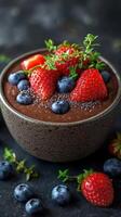 Fresh fruit topped chocolate dessert served in a dark bowl on a textured surface photo