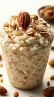 Creamy rice pudding with almonds served in a glass topped with nuts and oats at a cozy kitchen table photo