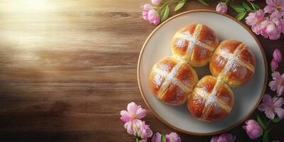 Freshly baked hot cross buns arranged on a plate with pink flowers in a cozy setting during springtime photo