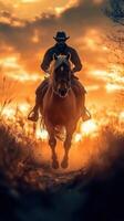 Rider gallops through a field at sunset against a backdrop of vibrant orange skies photo