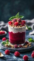 Delicious dessert with layers of chia pudding, raspberry compote, and granola garnished with fresh berries and mint photo