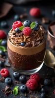 Delicious chocolate mousse layered with fresh raspberries and blueberries in a stylish glass bowl photo