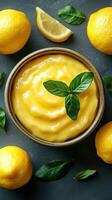 Delicious lemon curd in a bowl surrounded by fresh lemons and basil leaves on a dark surface photo