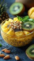 Fresh tropical fruit bowl with kiwi, pineapple, and chia seeds served in clear glass on blue background photo