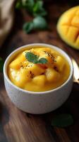 Delicious mango pudding with fresh mint leaves garnished in a speckled bowl on a wooden surface photo