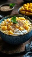 Delicious mango rice pudding served in a blue bowl with fresh mint and sesame seeds on a rustic wooden table photo